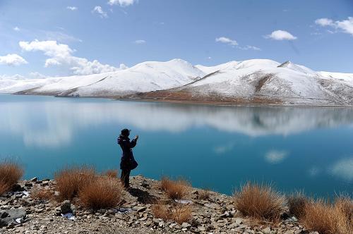 3月30日,，一位游客在羊卓雍湖畔拍照